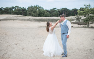 Trouwen in Bergen op Zoom. Bruidegom geeft de bruid een handkus terwijl ze poseren.
