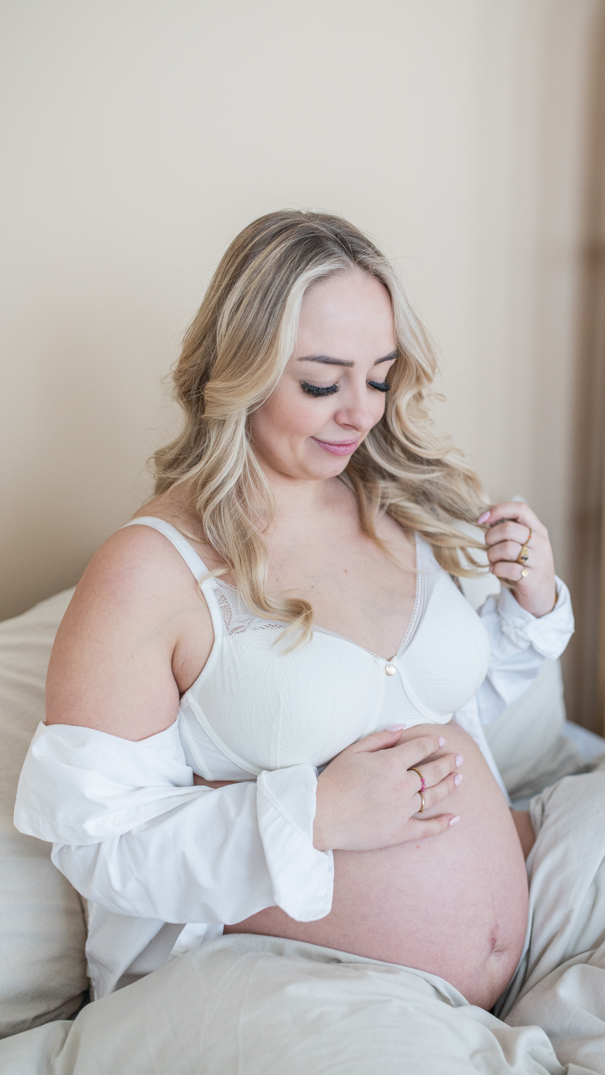 Puur Geluk Fotografie legt een intiem zwangerschapsportret vast in een lichte, huiselijke setting, waar een aanstaande moeder rustig zit en haar buik vasthoudt, natuurlijk en puur gefotografeerd.